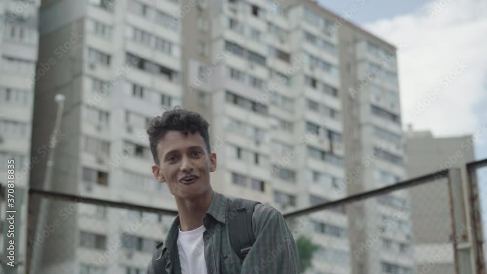 Portrait of positive young mixed-race rapper performing on urban city yard. Confident man singing rap and dancing outdoors on summer day. Retro styled guy having fun. Portrait of positive young mixed-race rapper performing on urban city yard. Confident man singing rap and dancing outdoors on summer day. Retro styled guy having fun.