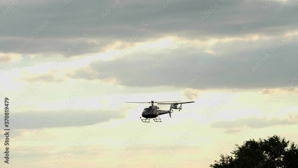 Retro airplane and a helicopter are flying over the treetops, against sunset sky with dark storm clouds. sun rays are breaking through the clouds Retro airplane and a helicopter are flying over the treetops, against sunset sky with dark storm clouds. sun rays are breaking through the clouds
