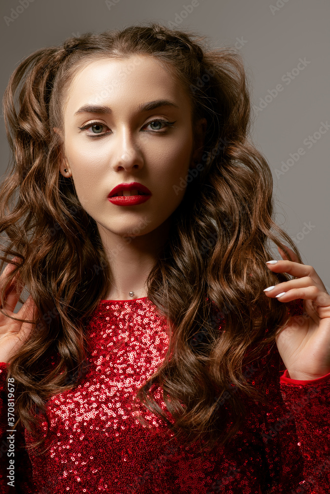 Fototapeta premium Close up beauty portrait of young attractive brunette woman with eyelines, red lips makeup, long waved hair, posing in studio, on gray background