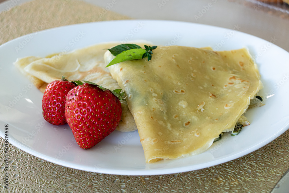 Close up of crepes with strawberries served on a white plate Close up of crepes with strawberries served on a white plate