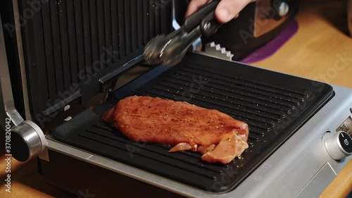 Raw meat sprinkled with spices spread on the grill