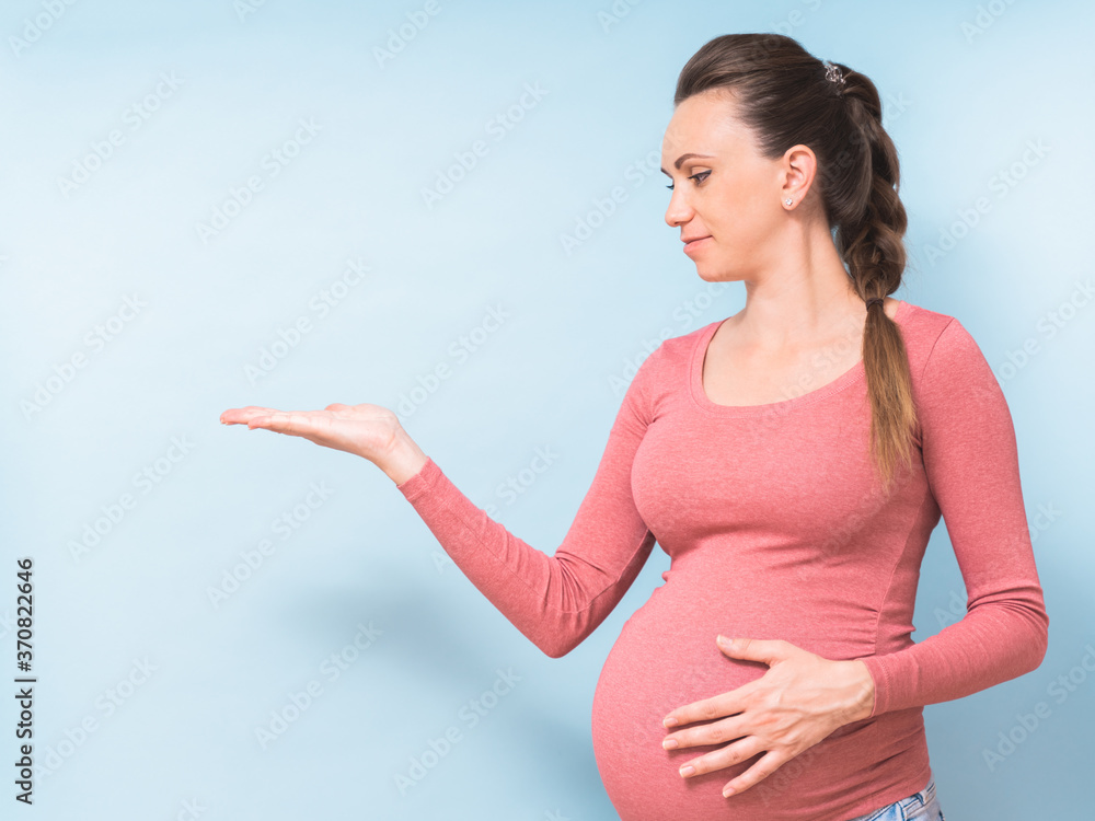 Young beautiful pregnant woman over isolated blue background pointing finger to the side showing product. Presenting your product. Copy space Young beautiful pregnant woman over isolated blue background pointing finger to the side showing product. Presenting your product. Copy space