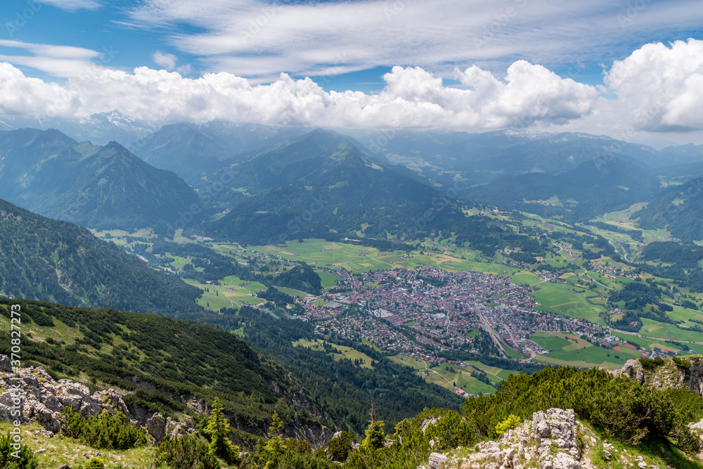 View from the summit of the mountain Rubihorn to the town Oberstdorf down in the valley with the Allgäu mountains in the background.