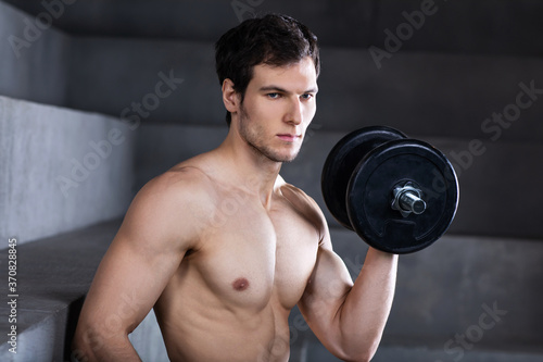 Closeup of a muscular young man with dumbbell.
