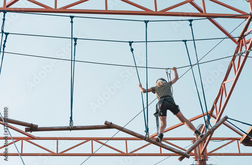Girl on a wood rope trail in an adventure park in city outdoor activity