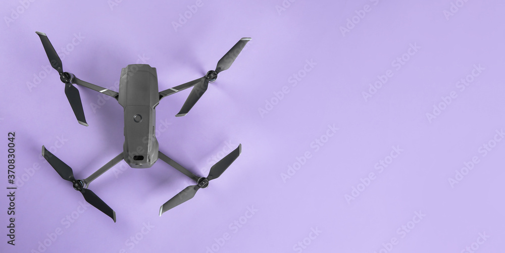 Modern drone with camera on lilac background, top view. Space for text Modern drone with camera on lilac background, top view. Space for text