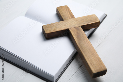 Christian cross and Bible on white wooden background, closeup. Religion concept