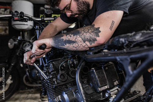 Side view of crop male mechanic using socket wrench and fixing motorbike in workshop