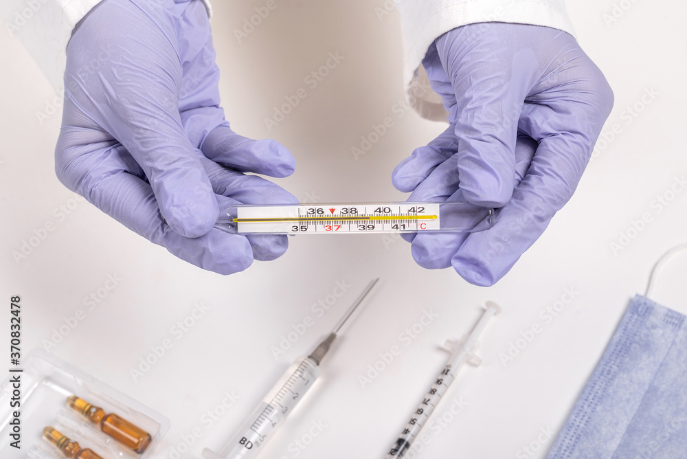 medical worker in blue gloves holds a thermometer medical worker in blue gloves holds a thermometer