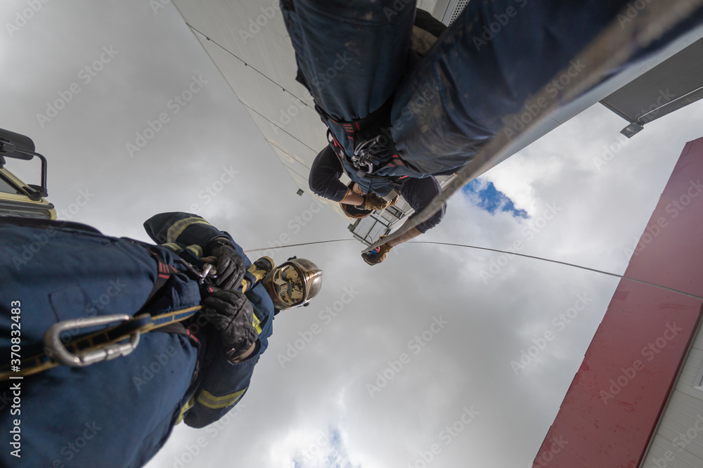 From below of rescue team of firemen standing in spacious complex and preparing for workout with ropes From below of rescue team of firemen standing in spacious complex and preparing for workout with ropes