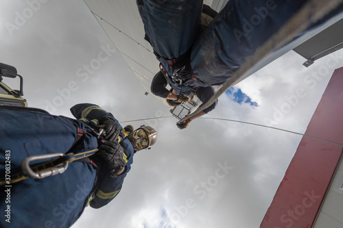 From below of rescue team of firemen standing in spacious complex and preparing for workout with ropes