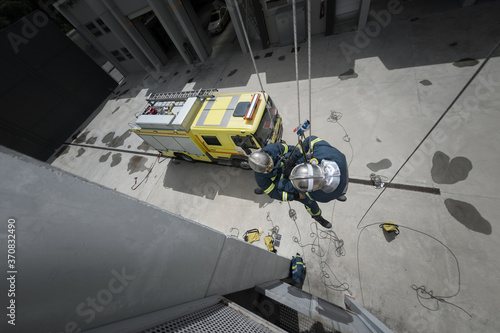 From above of firefighters in protective equipment climbing ropes near building during training photo