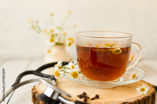 Decoction of chamomile, dried flower in flower tea and a phonendoscope, sliced lemon on a white wooden background. Health concept, prostate treatment, doctor prescribing treatment