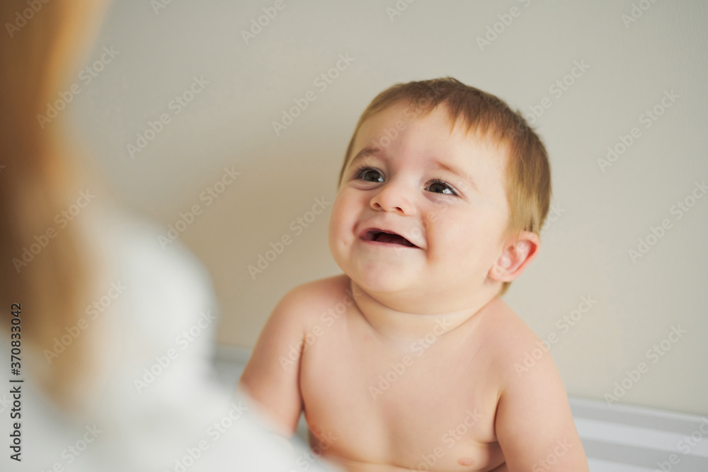 Little cheerful baby looking at anonymous mother and enjoying time together at home Little cheerful baby looking at anonymous mother and enjoying time together at home