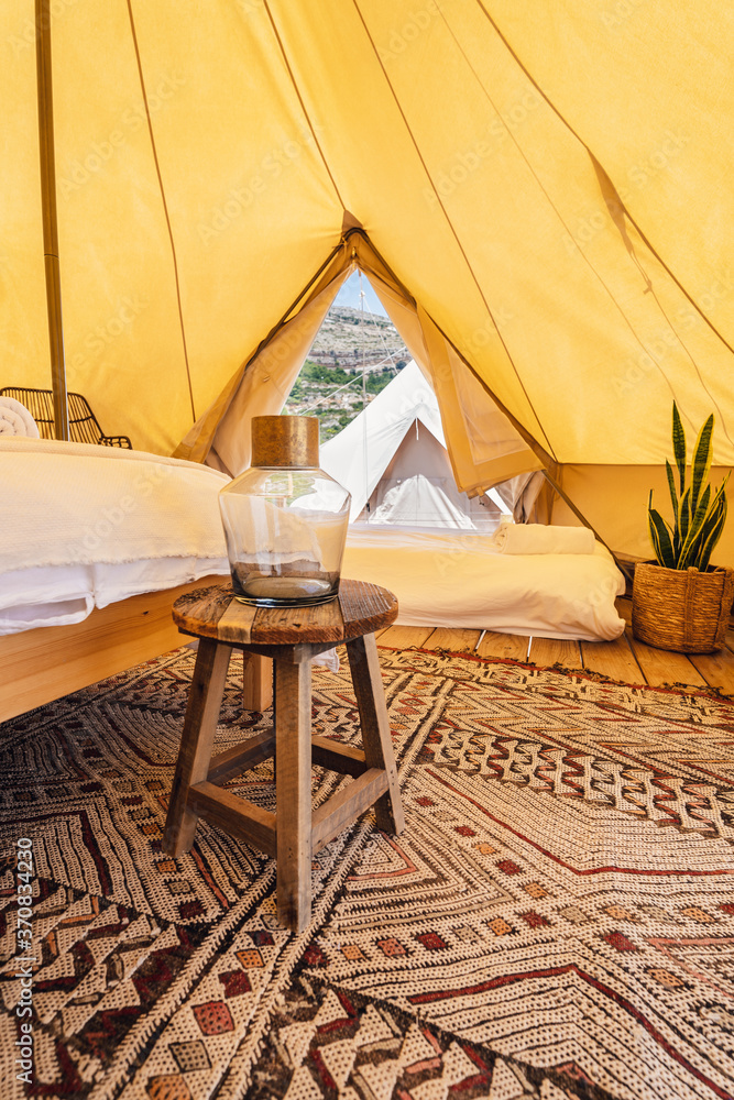 Amazing interior design of spacious cozy camping tent with comfy beds and creative lamps placed on carpet in tropical resort Amazing interior design of spacious cozy camping tent with comfy beds and creative lamps placed on carpet in tropical resort