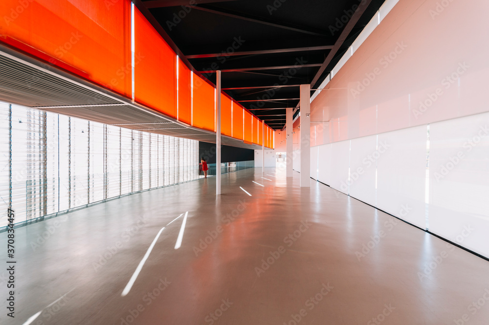 © Javier Bravo/ADDICTIVE STOCK - Side view of unrecognizable female standing on shiny concrete grey floor of passage in modern orange building © Javier Bravo/ADDICTIVE STOCK - Side view of unrecognizable female standing on shiny concrete grey floor of passage in modern orange building