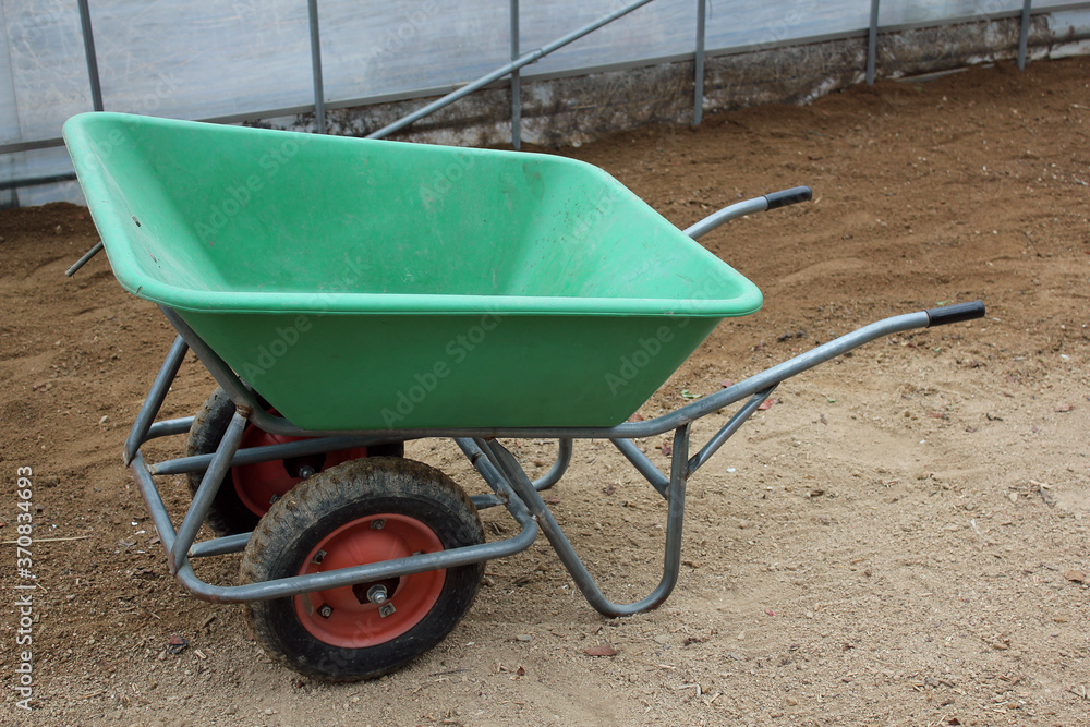 Two-wheeled wheelbarrow ( hand cart ) in a green house Two-wheeled wheelbarrow ( hand cart ) in a green house