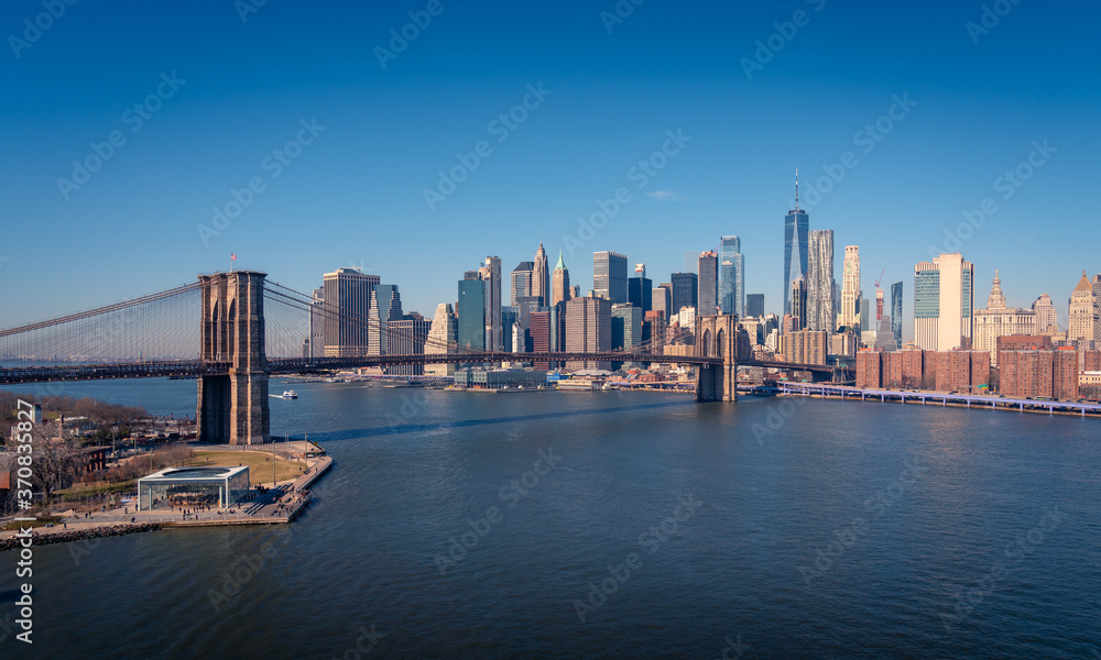 Amazing New York city skyline with famous Brooklyn bridge over river against cloudless blue sky in sunny day Amazing New York city skyline with famous Brooklyn bridge over river against cloudless blue sky in sunny day