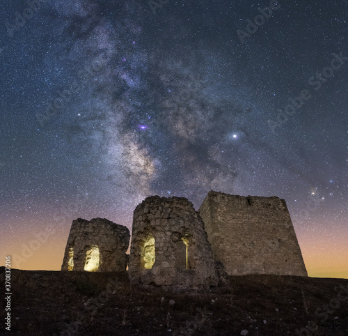 Castle on rough rocky mountain under spectacular scenery with luminous sky and Milky Way photo