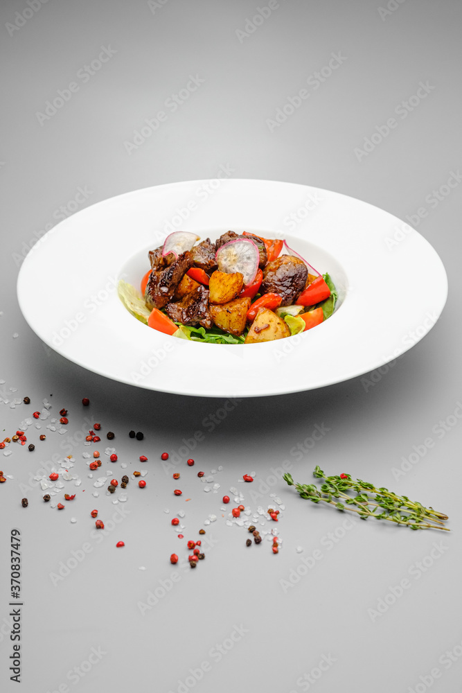 Meat salad with potatoes and grilled vegetables on a white plate. Meat salad with potatoes and grilled vegetables on a white plate.