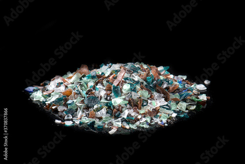Heap of colorful regrind polyethylene placed on black table in dark studio photo