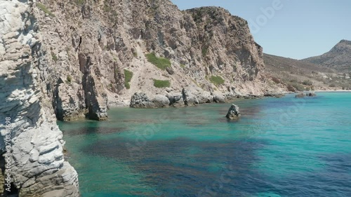 Slow Dolly Aerial in between rock fomations in Turquoise Blue Ocean Water on Greek Island Milos photo