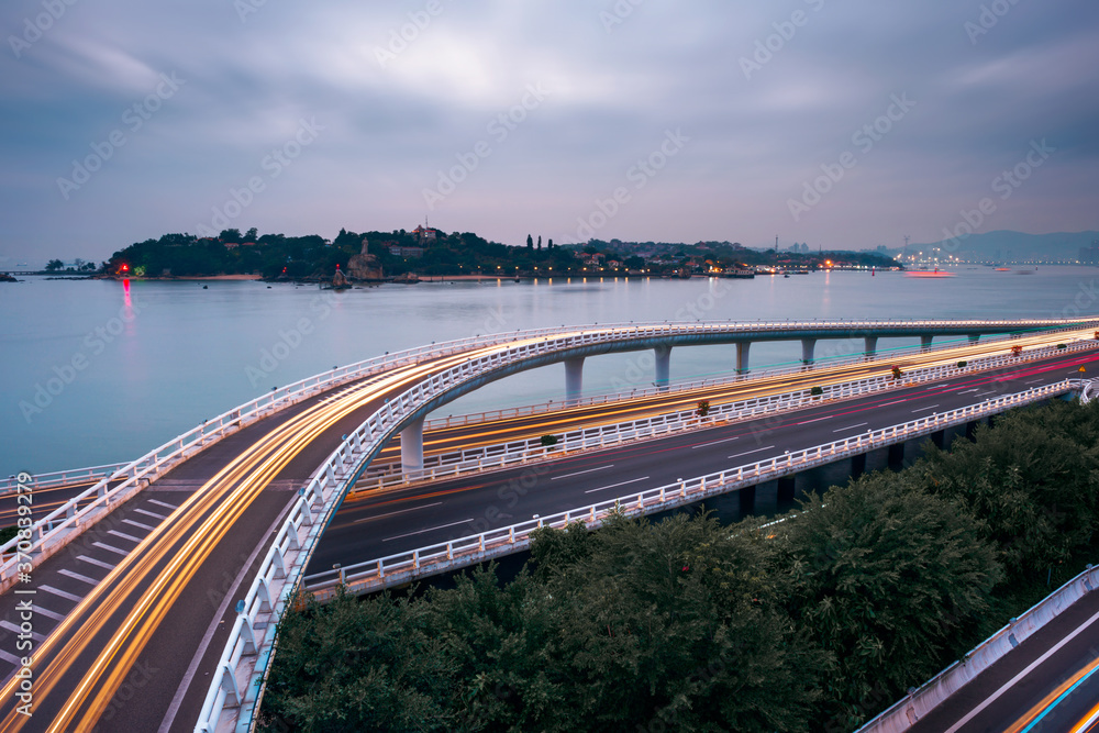From above of modern elevated highway intersection with marking lines without cars leading along sea coast in Xiame city in China during evening time