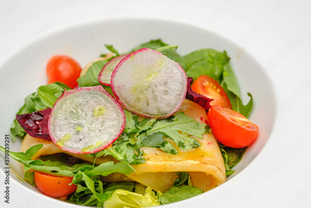 Squid with vegetables, tomatoes, salad and radishes on a white plate. Squid with vegetables, tomatoes, salad and radishes on a white plate.