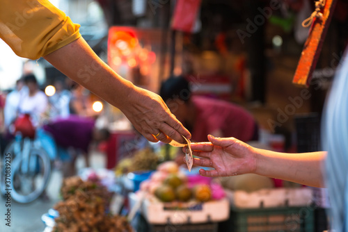 Side view of crop anonymous customer paying with banknote to seller in local street market in Xiamen city in China photo