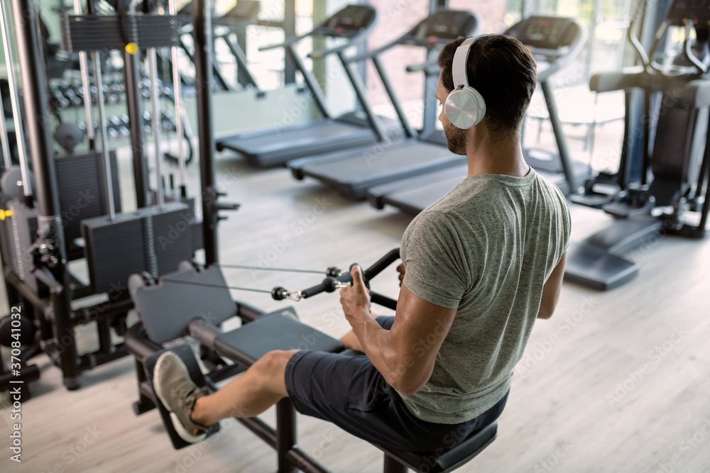 Athletic man exercising on rowing machine during cross training in a gym. Athletic man exercising on rowing machine during cross training in a gym.