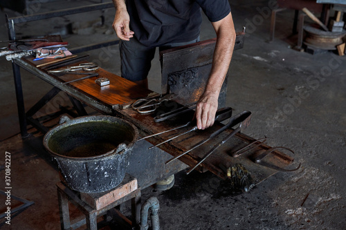 Above view of arranged shears with parchoffi and tweezers on metal workbench in workshop of glass blower photo