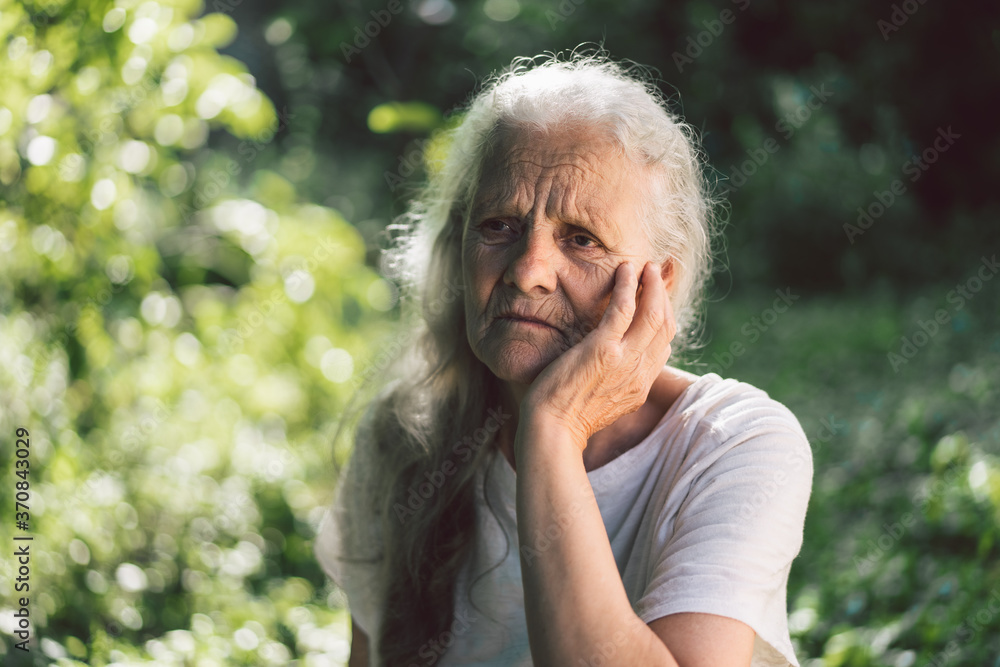 Portrait of a gray-haired adult grandmother against the background of nature