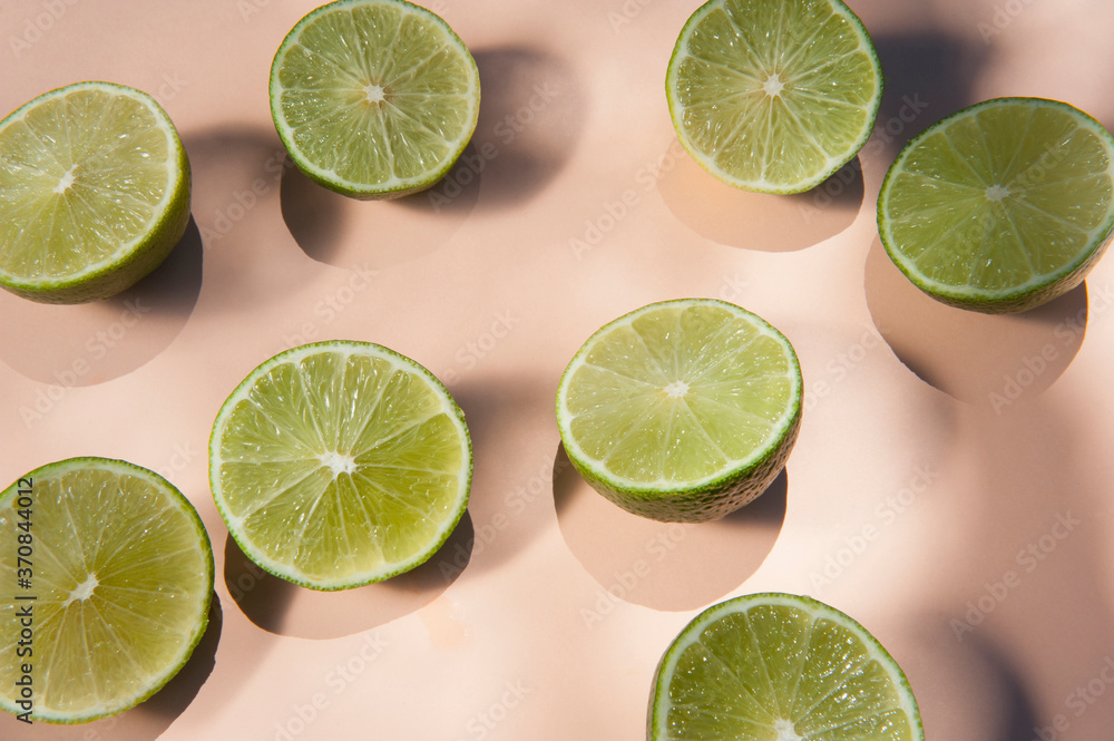 From above of halves of ripe limes arranged on pink background in modern studio From above of halves of ripe limes arranged on pink background in modern studio