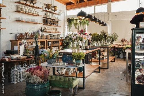 Interior of modern floral shop with various bouquets and decorative pots and vases arranged on wooden counters and shelves inside spacious pavilion