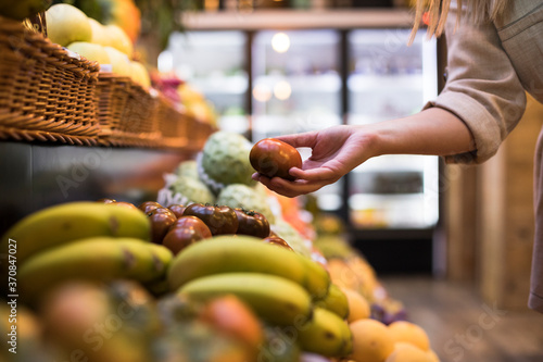 Cropped image of woman buying tomatoes at grocery store photo