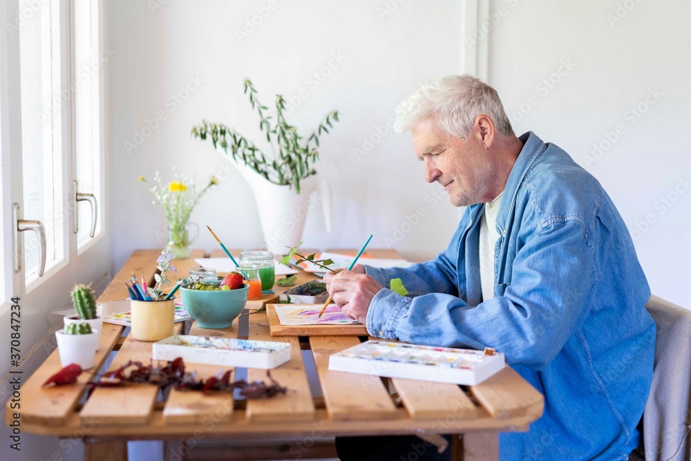 Senior man painting on table at home Senior man painting on table at home