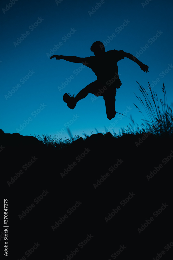 Silhouette of a runner jumping down a hill under the moonlight Silhouette of a runner jumping down a hill under the moonlight