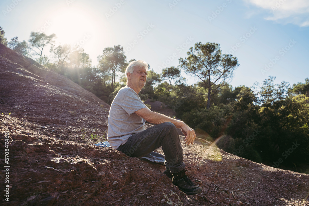 Senior man sitting on ground during break Senior man sitting on ground during break