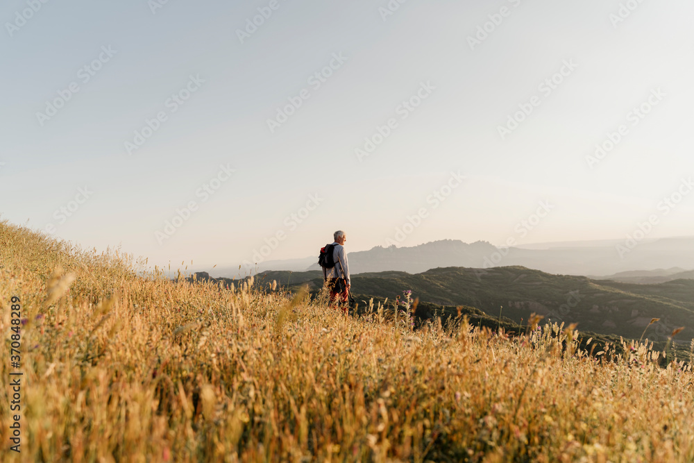Active senior man looking at landscape while standing on mountain Active senior man looking at landscape while standing on mountain