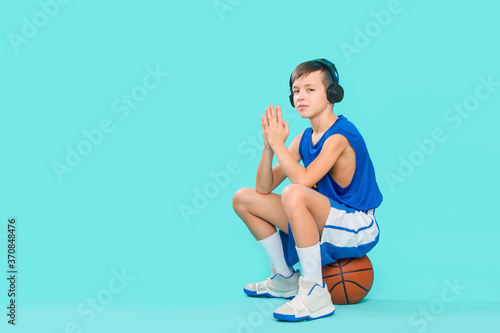 Kid with a ball for basketball enjoying music on his headphones, listening to music