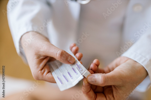 Acupuncture, female alternative practitioner opening package with acupunture needle