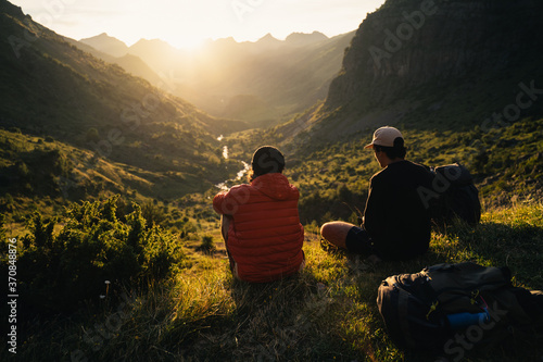 Two young men sitting on the grass watching the sunset on top of a valley in Pyrenees © Eneko Aldaz