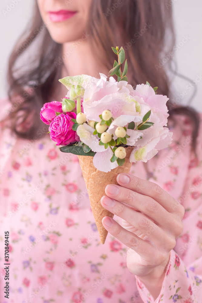 Women in vintage dress holding ice cream waffle cone with pink roses and hydrangea .Floral composition of beautiful spring fresh flowers isolated indoor. Florist at work.Copy Space.Food photo.