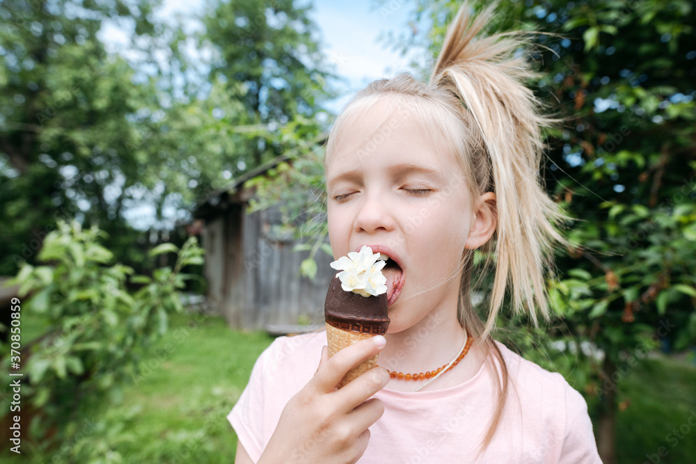 Portrait of blond girl with eyes closed eating ice cream with jasmine flowers in garden Portrait of blond girl with eyes closed eating ice cream with jasmine flowers in garden
