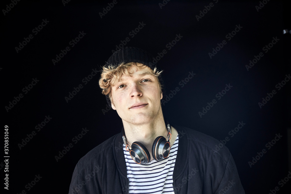 © Westend61 - Portrait of young man with headphones against black background