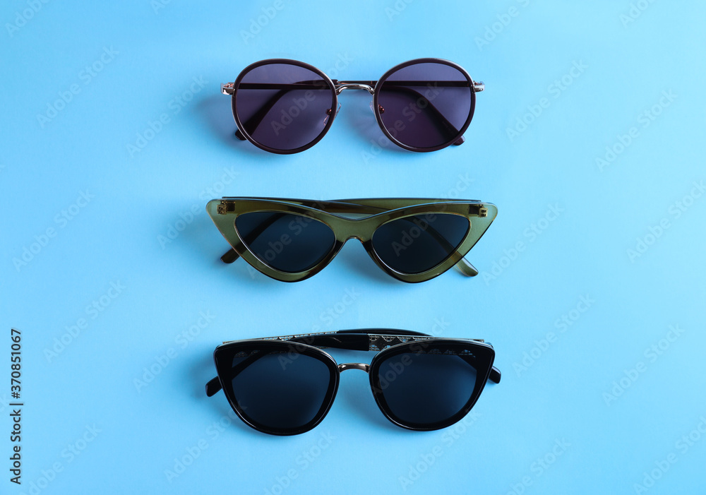 Many stylish sunglasses on light blue background, flat lay Many stylish sunglasses on light blue background, flat lay