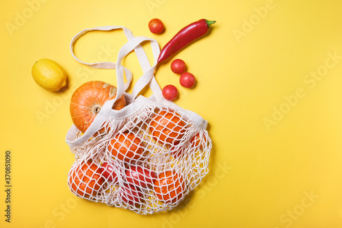 Juicy and fresh vegetables and fruits in ecological cotton reusable string bag, alternative to plastic bags, on white background.