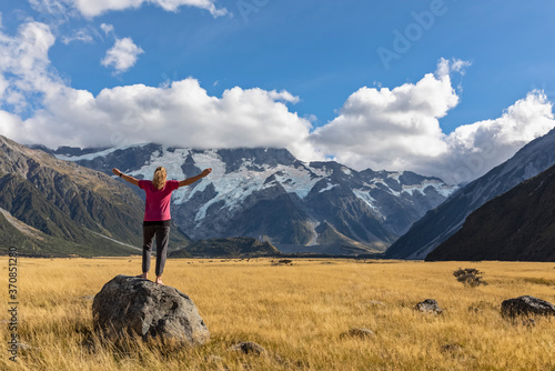 New Zealand, Oceania, South Island, Canterbury, Ben Ohau, Southern Alps (New Zealand Alps), Mount Cook National Park, Aoraki / Mount Cook, Woman standing on boulder in mountain landscape photo