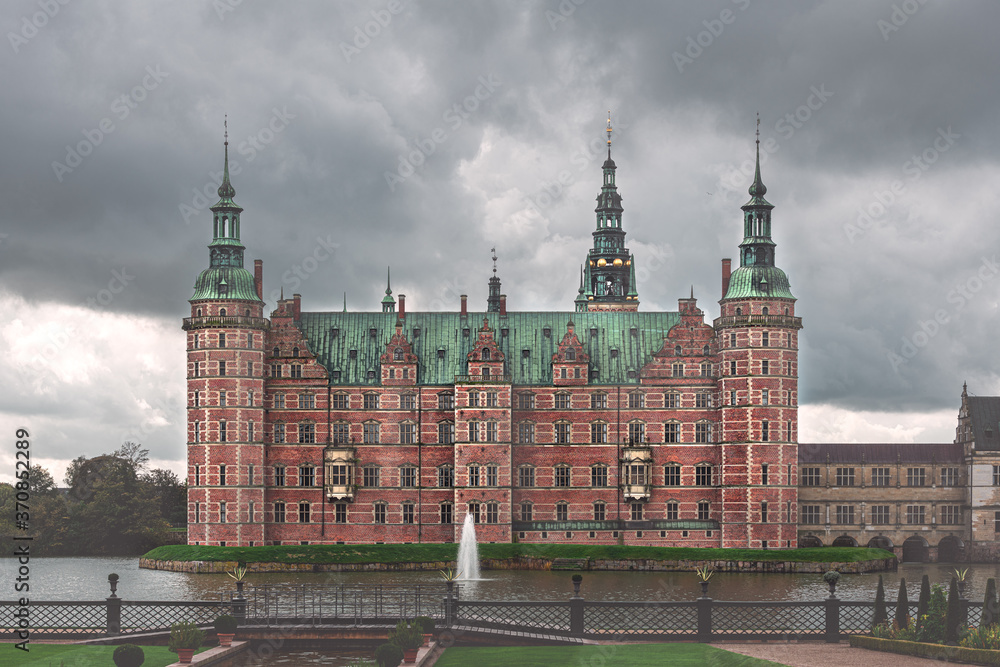 Frederiksborg slot facade view from lake side on background of cloudy sky