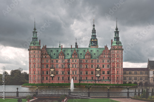 Frederiksborg slot facade view from lake side on background of cloudy sky